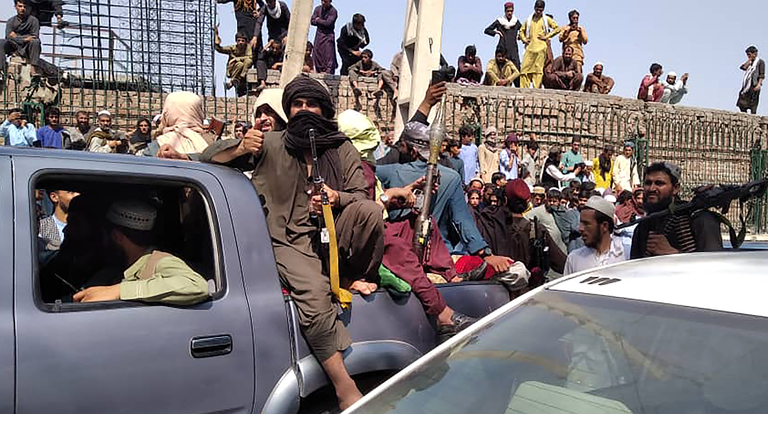 Taliban fighters sit on a vehicle along the street in Jalalabad province