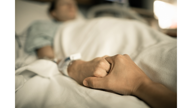 Man holding woman hand in hospital bed. Holding hands in hospital bed