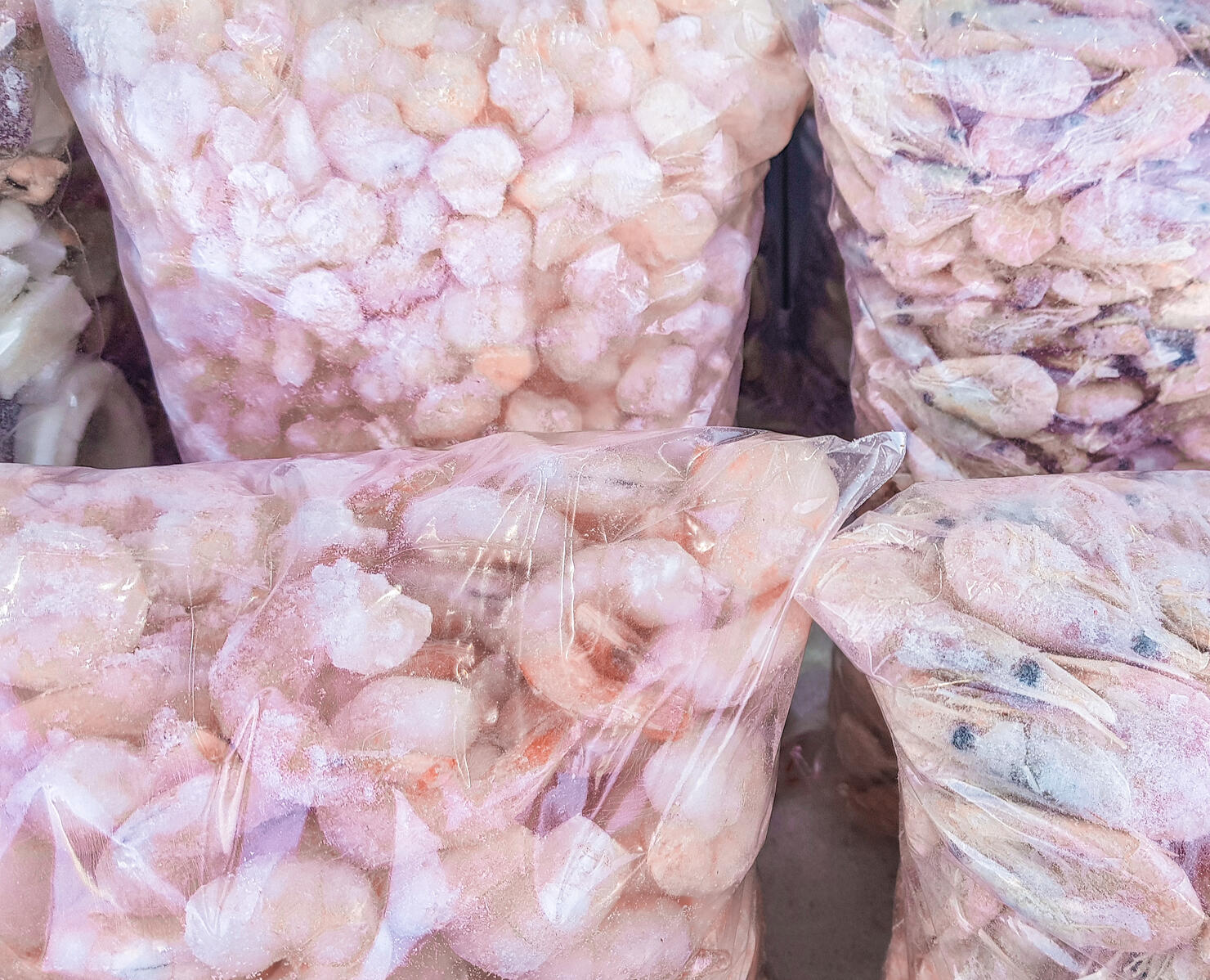 Transparent plastic bag with large king prawns, frozen seafood on the counter of the fish market, wholesale, background of frozen food with snow and frost