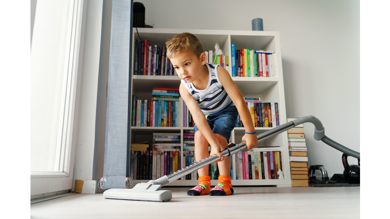 Little kid using vacuum cleaner at home - Small boy cleaning floor in apartment - Child doing housework having fun - side view full length in summer day - childhood development real people concept