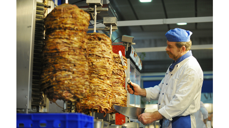 A man carves gyros meat at the Greek sta