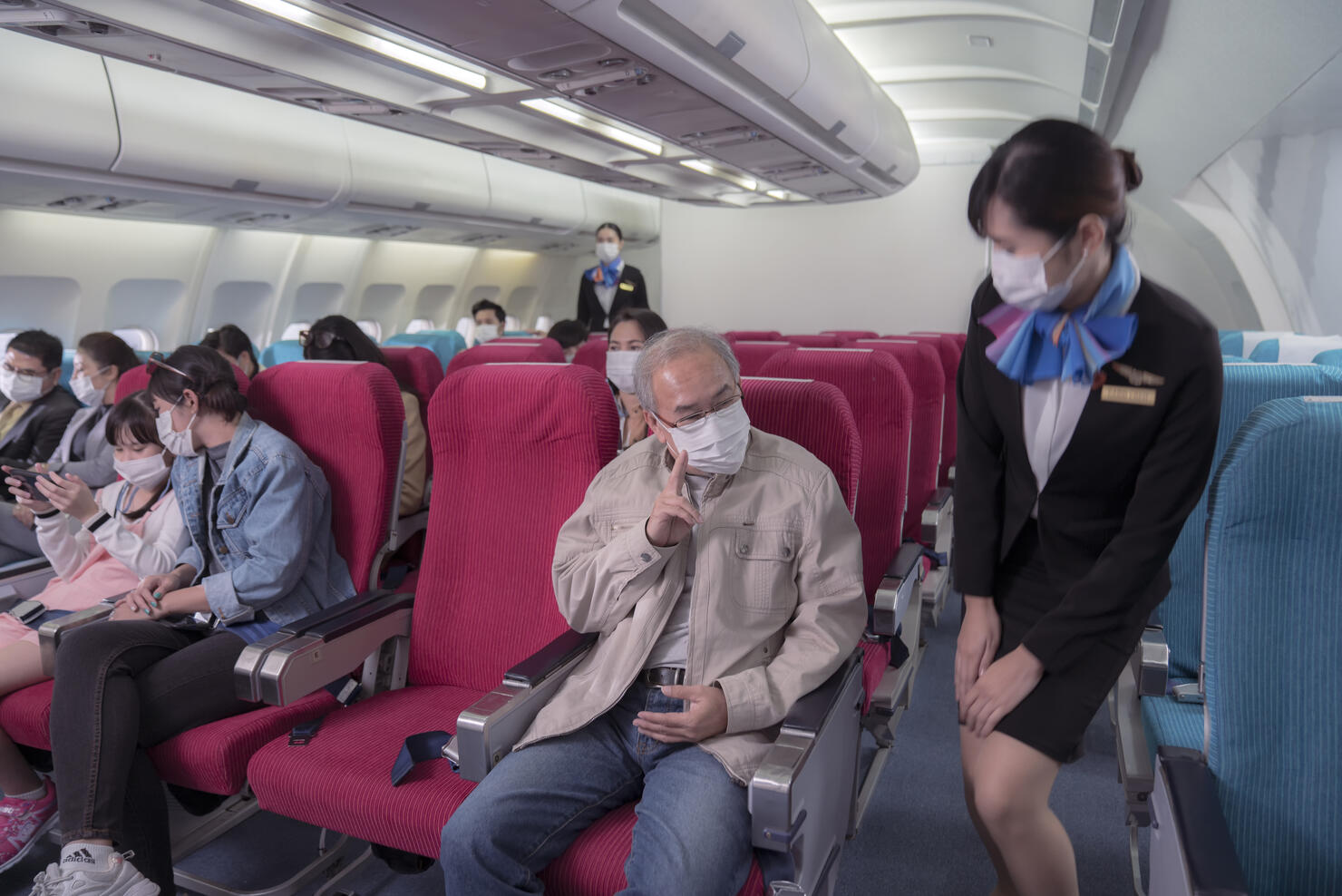 Cabin crew serve  to elderly male passenger  in airplane . Airline transportation and tourism concept.