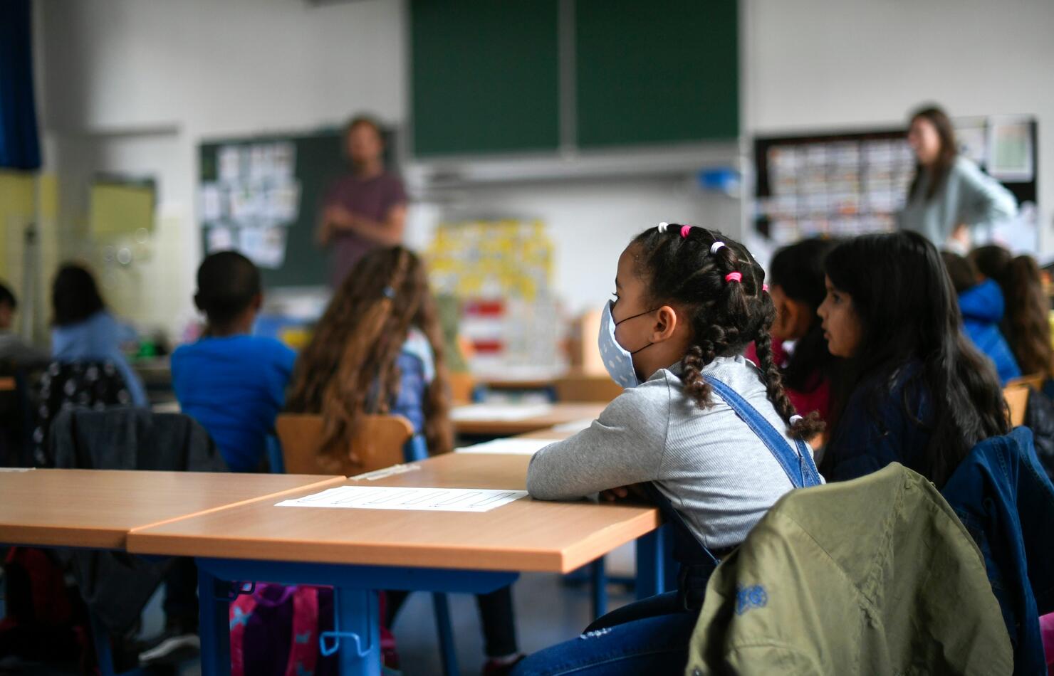 Girl wearing a face mask sits in a classroom. 