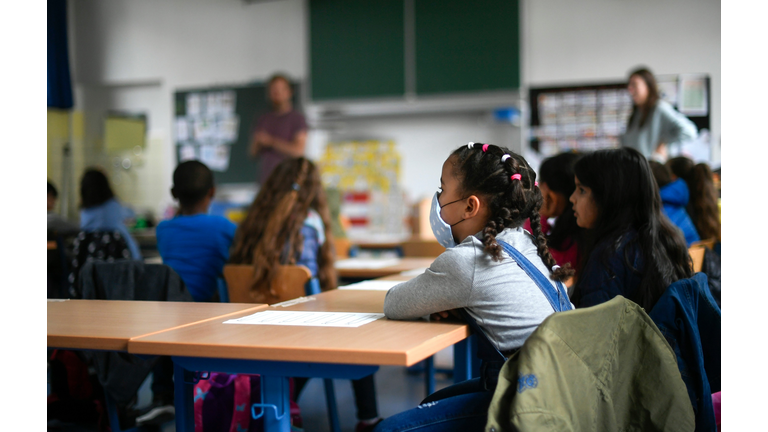 Girl wearing a face mask sits in a classroom. 