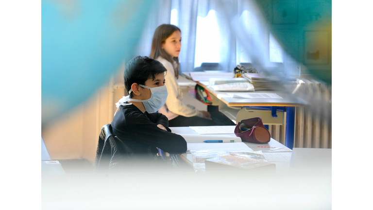 Boy sits at desk with mask on