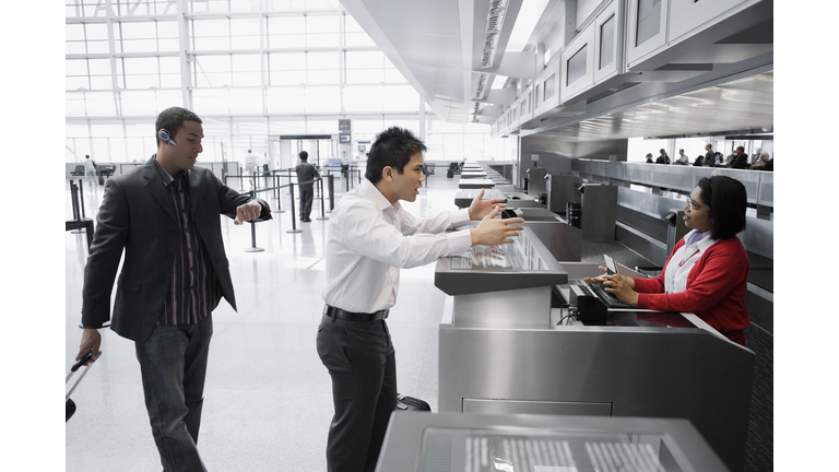 Businessman shouting at an airline check-in attendant