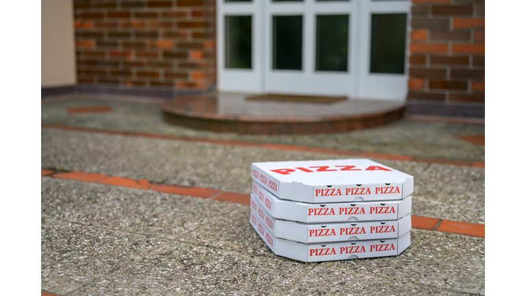 Pizza boxes on the floor in front of a door of a house
