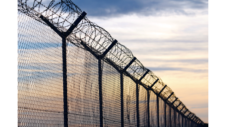 Silhouette of Barbed Wire fence against a Cloudy Sky