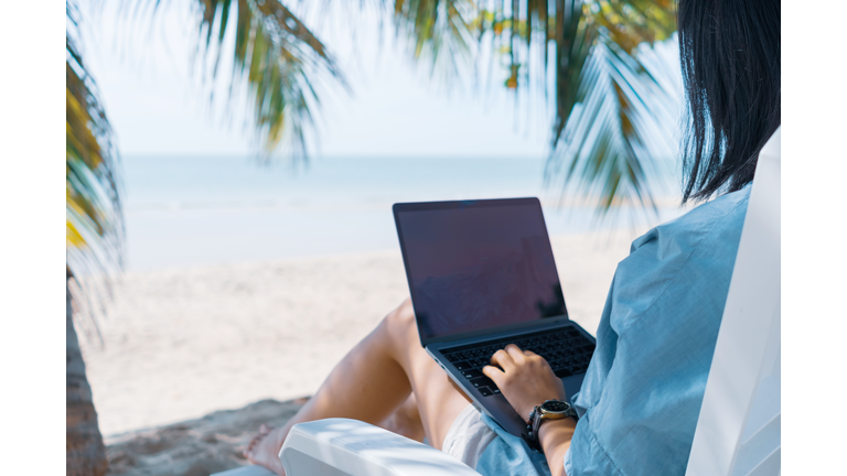 Woman using laptop and smartphone to work study in vacation cady at beach background. Business, financial, trade stock maket and social network concept.