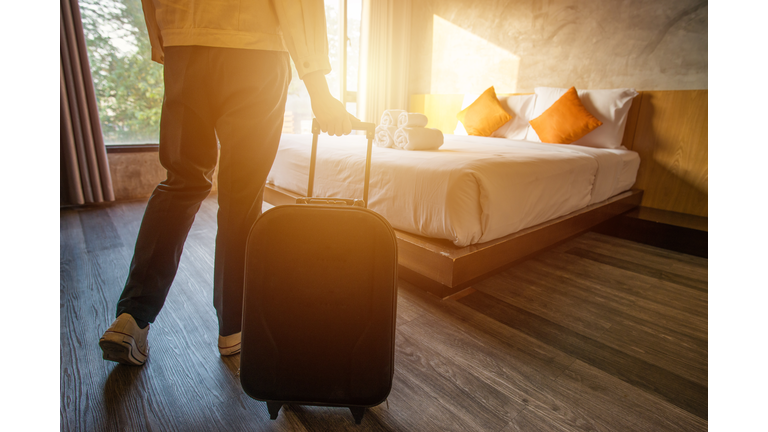 Cropped shot of tourist woman pulling her luggage to her hotel bedroom after check-in.