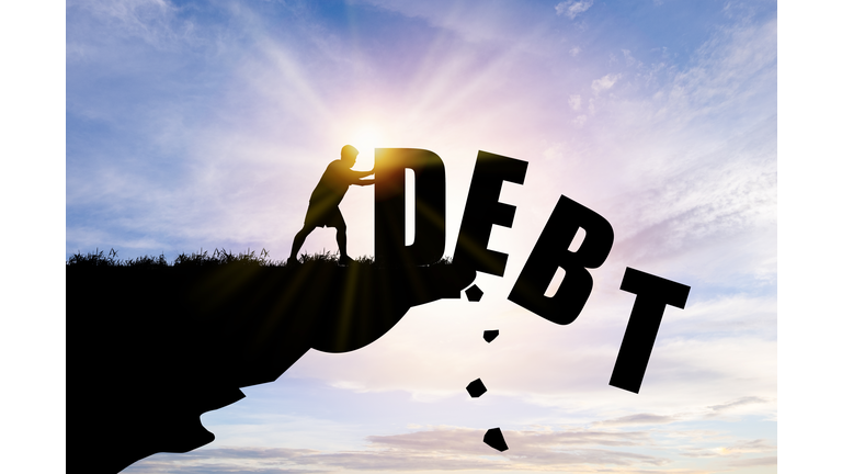Eliminate or get rid of debt concept , Silhouette man pushed off debt wording a cliff with blue cloud sky and sunlight.