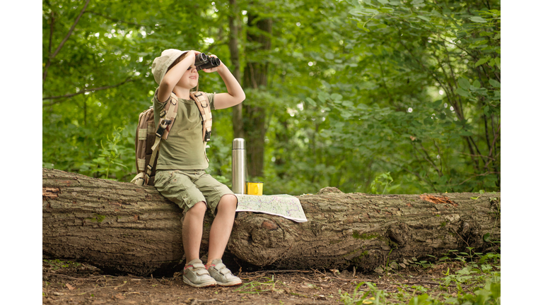 girl looking at birds through binoculars, camping in the woods