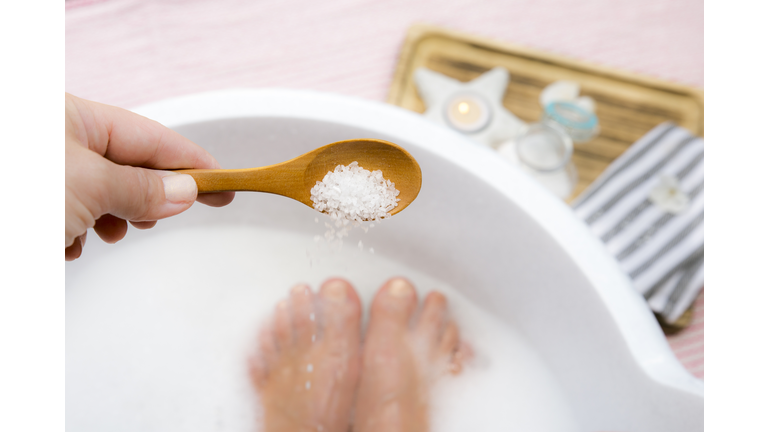 Adding Magnesium Chloride vitamin salt in foot bath water, solution. Magnesium grains in foot bath water are ideal for replenishing the body with this essential mineral, promoting overall wellbeing.