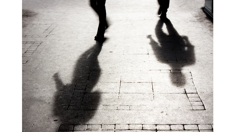 Shadow of a man on patterened sidewalk