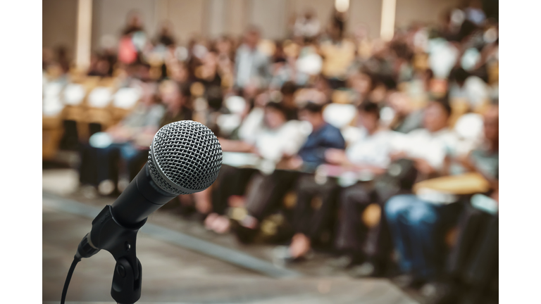 Microphone over the Abstract blurred photo of conference hall or seminar room with attendee background