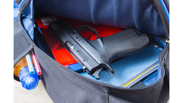Loaded 9mm pistol in the school backpack. School shootings, gun control concept image.