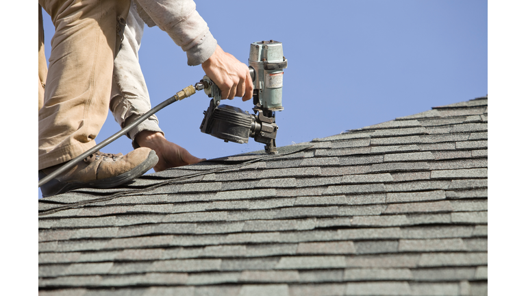 Roofer Nailing Cap Shingle to a New House Roof
