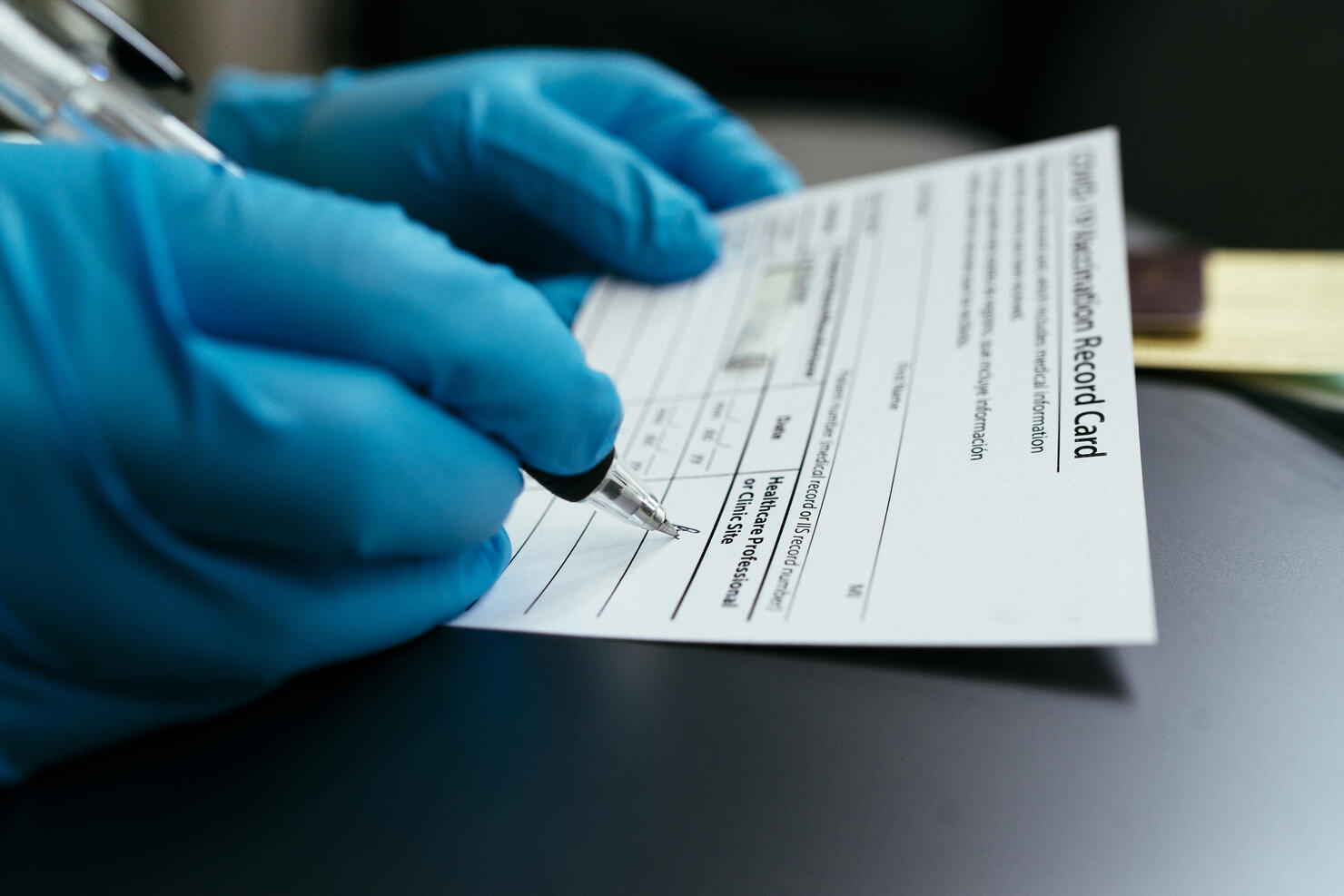 hand of Doctor wearing surgical glove and certify Vaccination card and passport for first dose Vaccine Covid-19 (coronavirus)