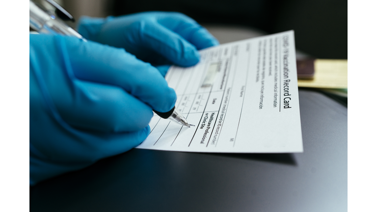 hand of Doctor wearing surgical glove and certify Vaccination card and passport for first dose Vaccine Covid-19 (coronavirus)