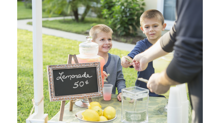 Boys with lemonade stand, taking payment from man