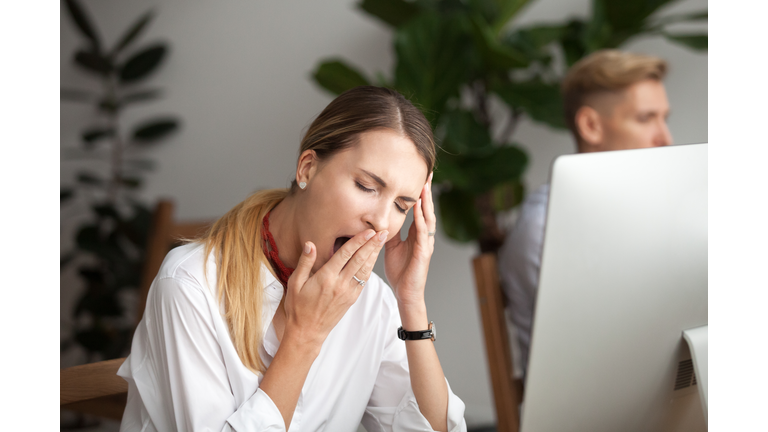 Bored tired businesswoman yawning at workplace feeling lack of sleep