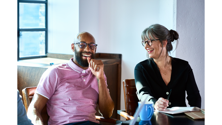 Cheerful mature businesswoman laughing with male coworker