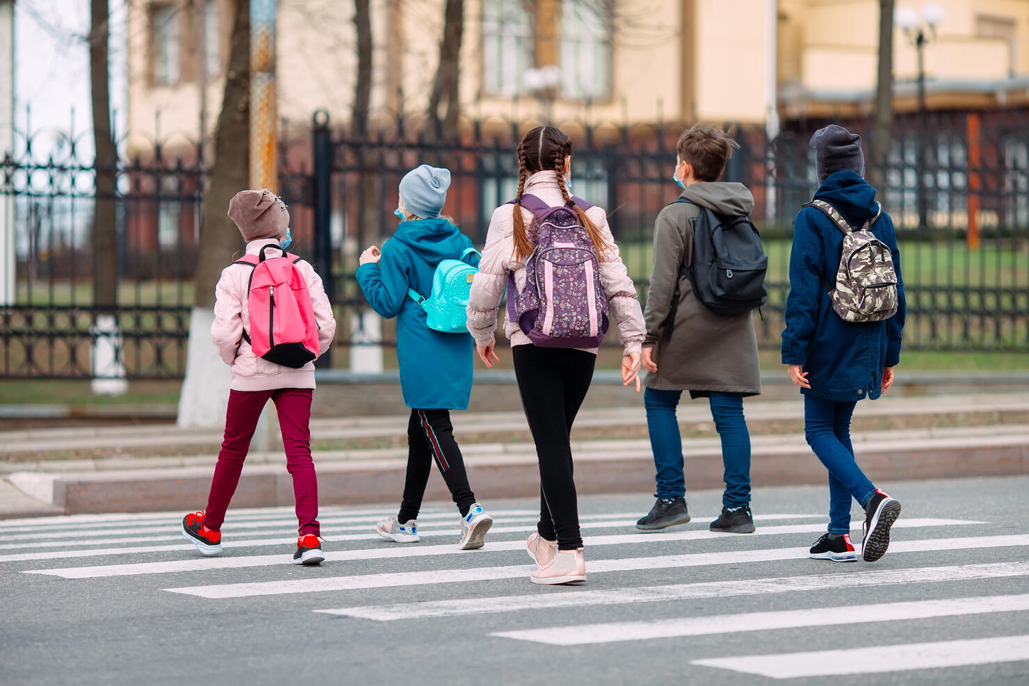 School children cross the road in medical masks. Children go to school.