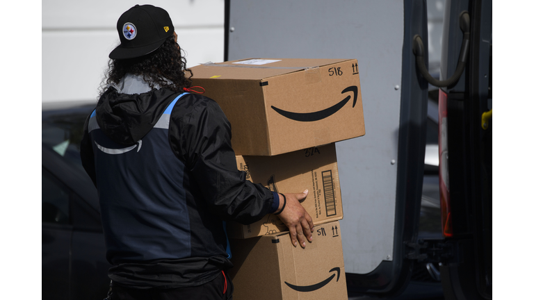 An Amazon.com Inc. delivery driver carries boxes into a van. 