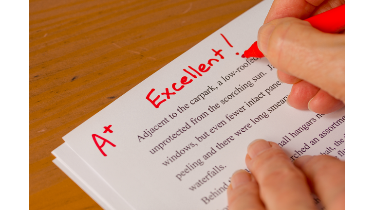 Hand and Red Pen Grading Papers with Excellent