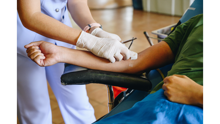 Nurse help patient to stop bleeding while donating blood.