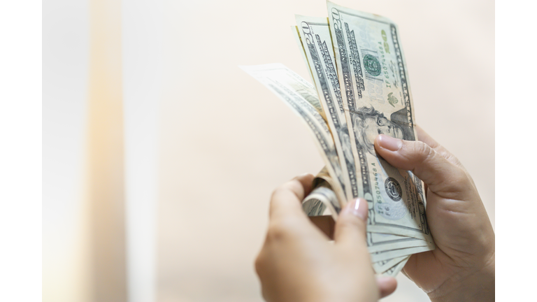 Money Business shopping and saving concept. Close up of woman hand holding and counting US Dollar banknote with copy space.