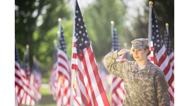 American female soldier saluting in a Field of American Flags