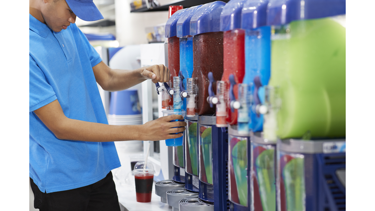 Male employee filling soda in cup from machinery