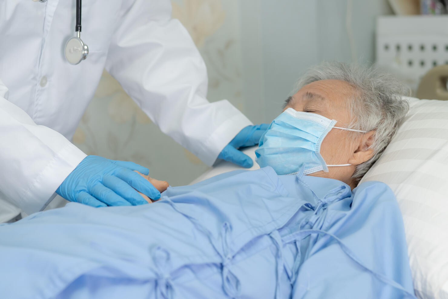 Doctor help Asian senior or elderly old lady woman patient wearing a face mask in hospital for protect safety infection and kill Novel Coronavirus (2019-nCoV) Covid-19 virus.