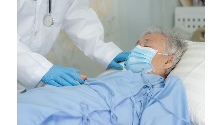 Doctor help Asian senior or elderly old lady woman patient wearing a face mask in hospital for protect safety infection and kill Novel Coronavirus (2019-nCoV) Covid-19 virus.