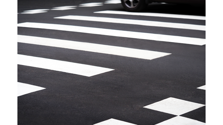 Road, pedestrian crossing closeup, car driving on a pedestrian crossing
