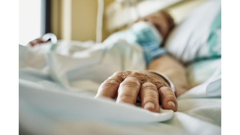 Senior woman wearing face mask lying on hospital bed