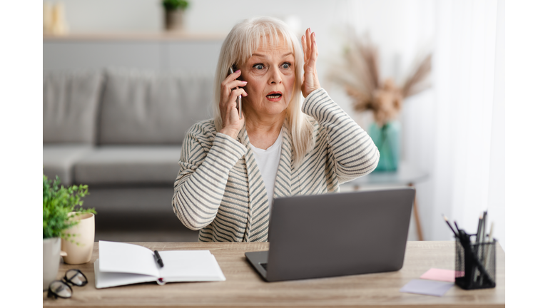 Surprised shocked mature woman talking on mobile phone