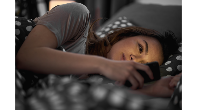Girl using smart phone and lying down in bed