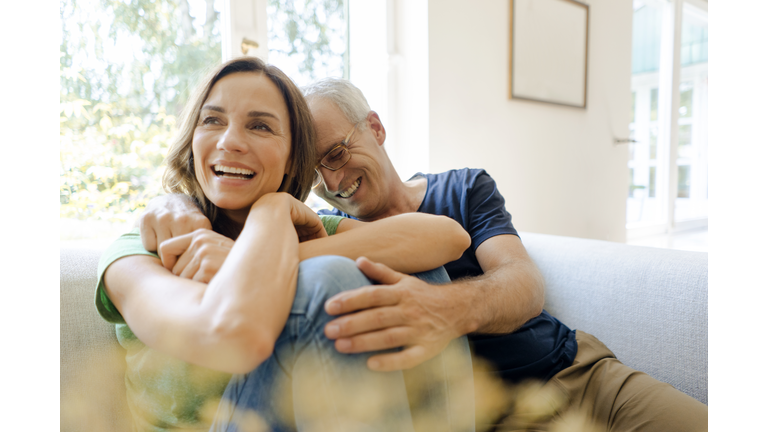 Happy mature couple sitting on couch at home