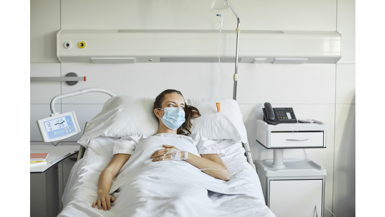 Sick female lying on bed in ICU during COVID-19