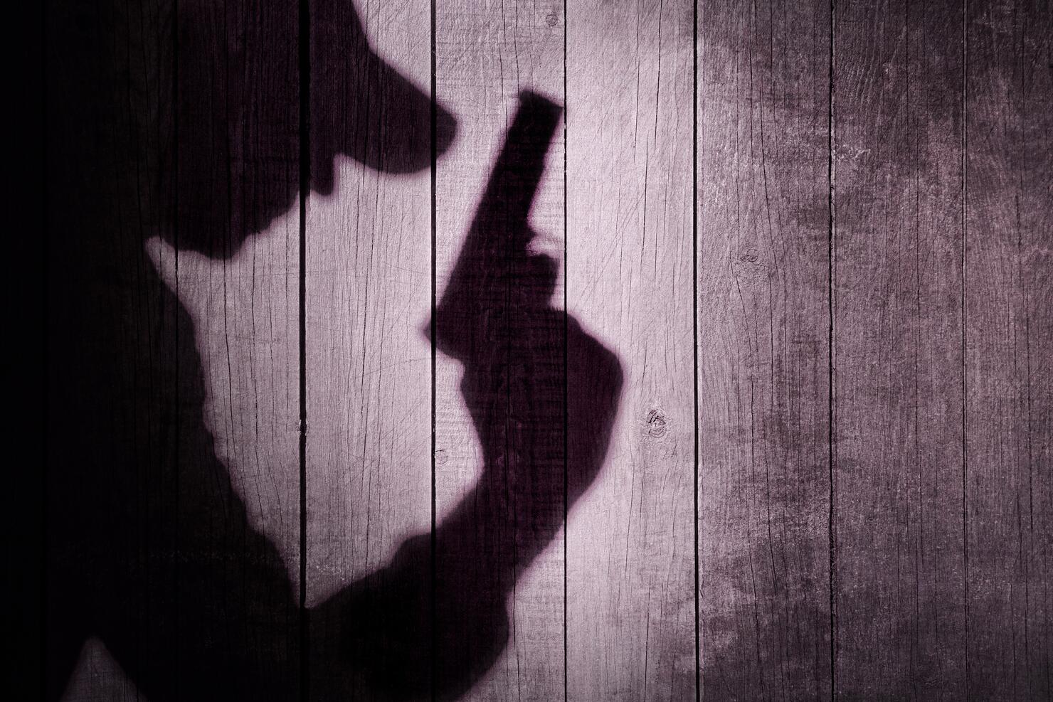 Gangster or investigator or spy silhouette on natural wooden wal