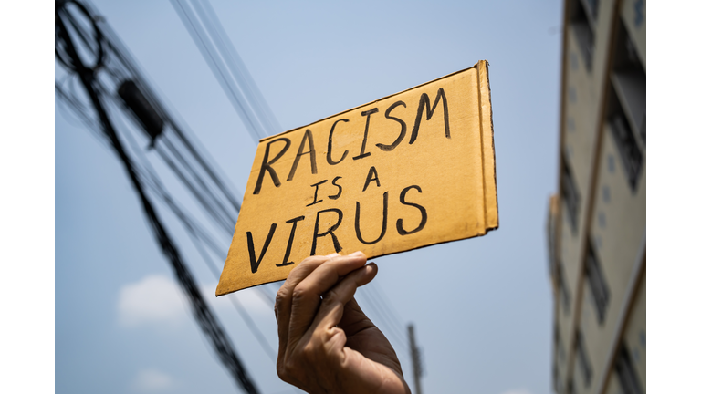 A man holding Racism is a Virus sign