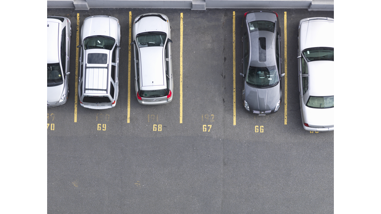 Overhead view of cars in parking lot, one empty 