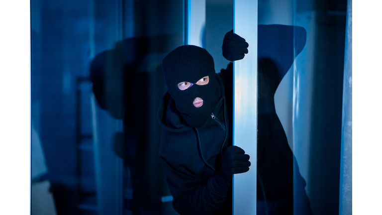 Burglar peeking into the house through an open glass door