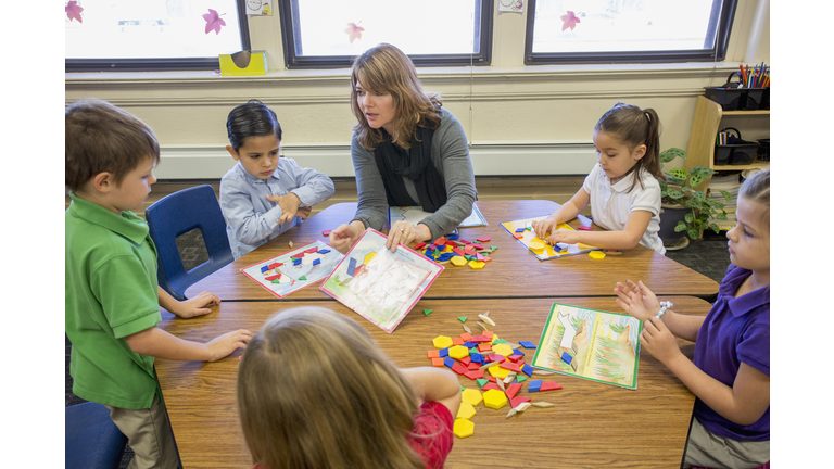 Caucasian teacher helping students with project in classroom