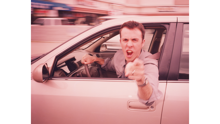 Man driving, leaning out of car, pointing angrily (blurred motion)