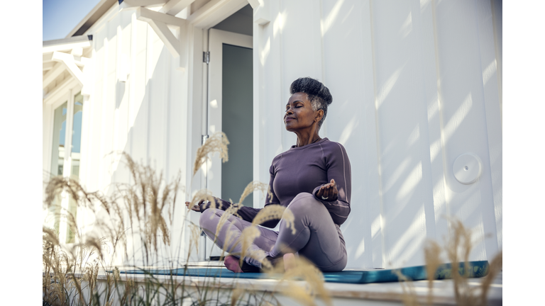 Mature woman meditating in backyard