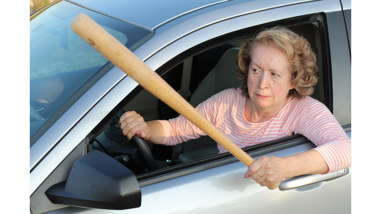 Angry mature female driver holding baseball bat