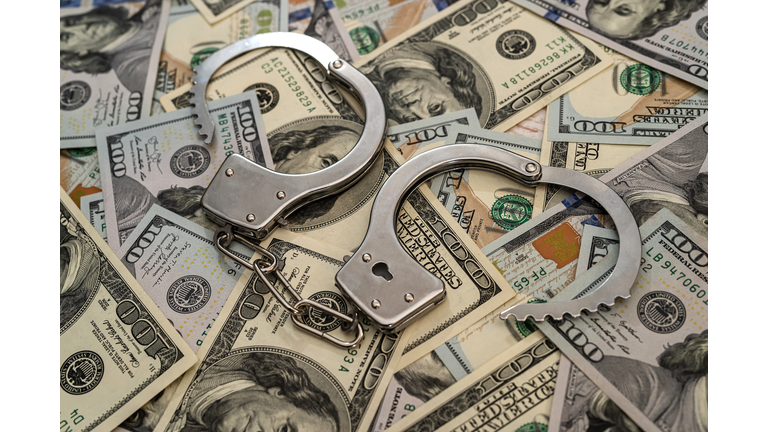 close up of metal handcuffs on hundred dollar banknotes